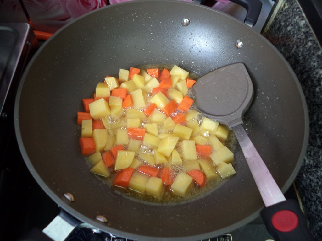 再把土豆和胡萝卜丁倒入油锅,滑炒片刻.