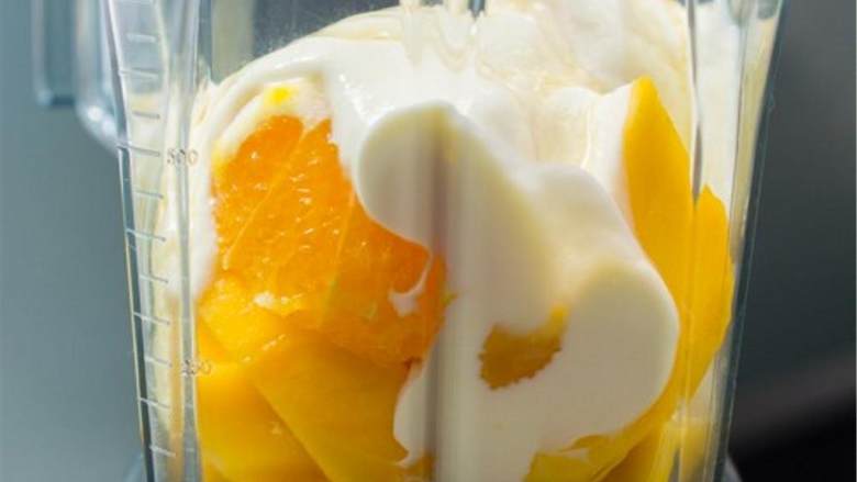 芒果橙子奶昔,把芒果和橙子加入搅拌器中,加入原味希腊酸奶,牛奶