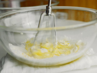 老酸奶舒芙蕾松饼,用打发过蛋清的打蛋器搅拌蛋黄盆.