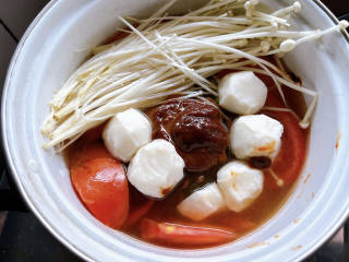 金针菇番茄汤,铺上金针菇和丸子，转大火煮至沸腾。