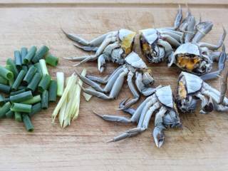 家常炒螃蟹,鲜活的螃蟹用刷子将外壳和蟹腿刷洗干净，然后从中间切成两半，切葱段和姜丝备用。