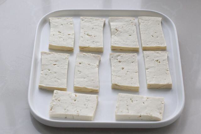 煎酿豆腐,将豆腐切成适量大小的块状，然后用厨房纸将表面水分吸干备用。
