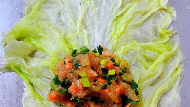白菜卷肉,处理好的白菜平铺在案板上取适量的馅料放在白菜的一侧