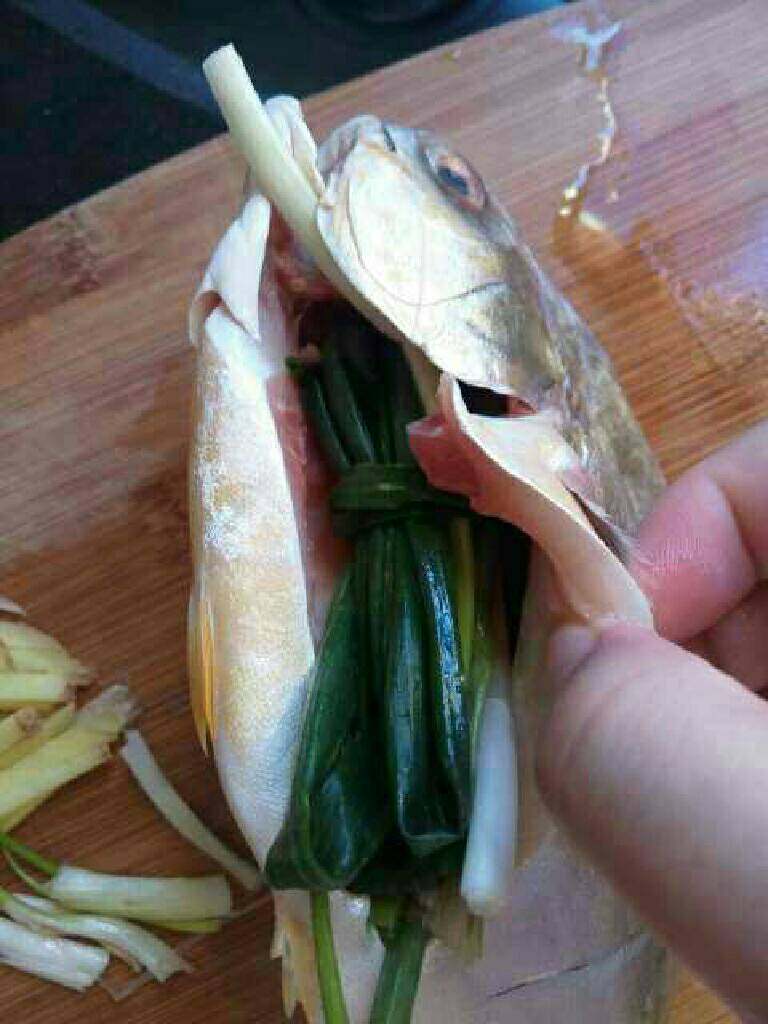 清蒸金鲳鱼,把处理好的鱼洗干净再把绑好的葱塞进鱼肚子里。