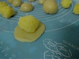 金沙奶黄月饼,如图取一饼皮按扁包入奶黄馅儿