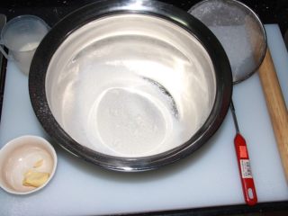 芝士榴莲披萨,用筛网过滤高筋面粉，加入糖、盐。酵母用80g温水泡开，分两次倒入面粉团。