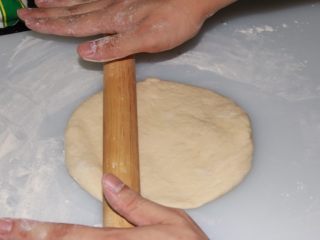 芝士榴莲披萨,不停按压面粉团 把多余的空气压出来，并用木棍推成饼底雏形，并且把烤箱预热至230℃。