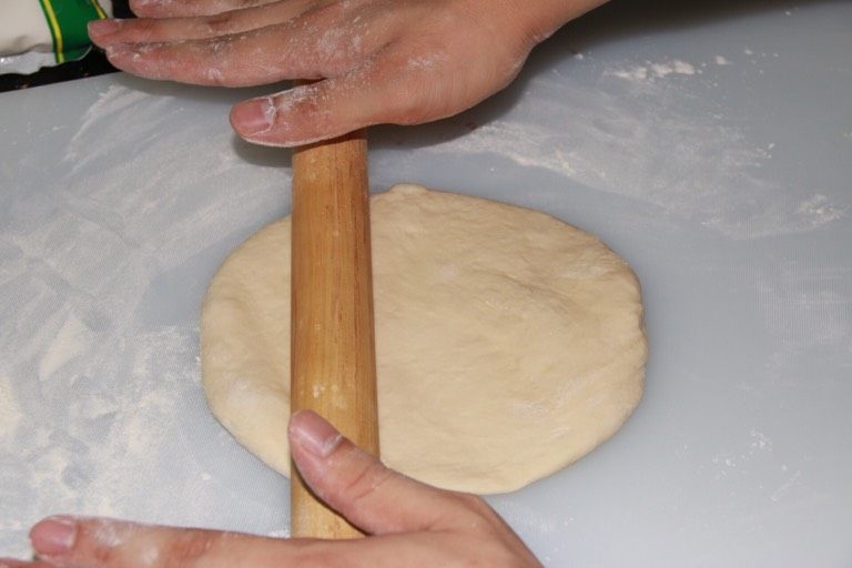 芝士榴莲披萨,不停按压面粉团 把多余的空气压出来，并用木棍推成饼底雏形，并且把烤箱预热至230℃。