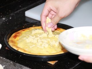 芝士榴莲披萨,12分钟后取出，再撒一层马苏里拉芝士碎条，并放回烤箱继续烤至融化（约3分钟）。