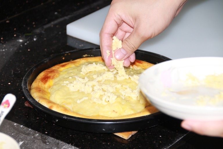 芝士榴莲披萨,12分钟后取出，再撒一层马苏里拉芝士碎条，并放回烤箱继续烤至融化（约3分钟）。