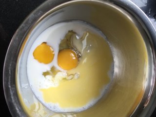 紫芋绵绵包,碗中放入主料中的鸡蛋、120克牛奶、5克糖粉、黄油用电动打蛋器搅打均匀