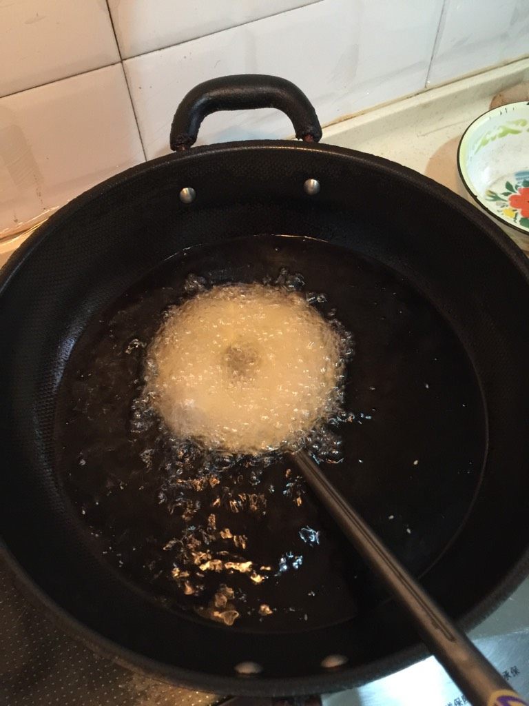 武汉面窝,将米桨倒入勺内，中间刮出小口，下油锅炸。