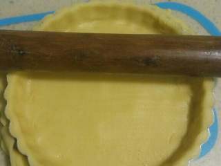 奶香南瓜派,将面片放在6寸派盘中，边缘和底部用手压实，用擀面杖擀去边缘多余的部分
