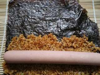 小熊寿司卷,再取一张海苔，铺上一半酱油饭，放上火腿肠。