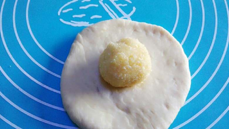 奶香椰蓉面包,取出一个小面团擀扁，放入椰蓉馅料，然后将馅料包起来搓成圆形。