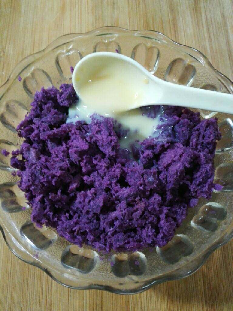 水晶南瓜饼,趁热把紫薯装入碗中，用勺子压成泥，加入一勺炼奶搅拌均匀。