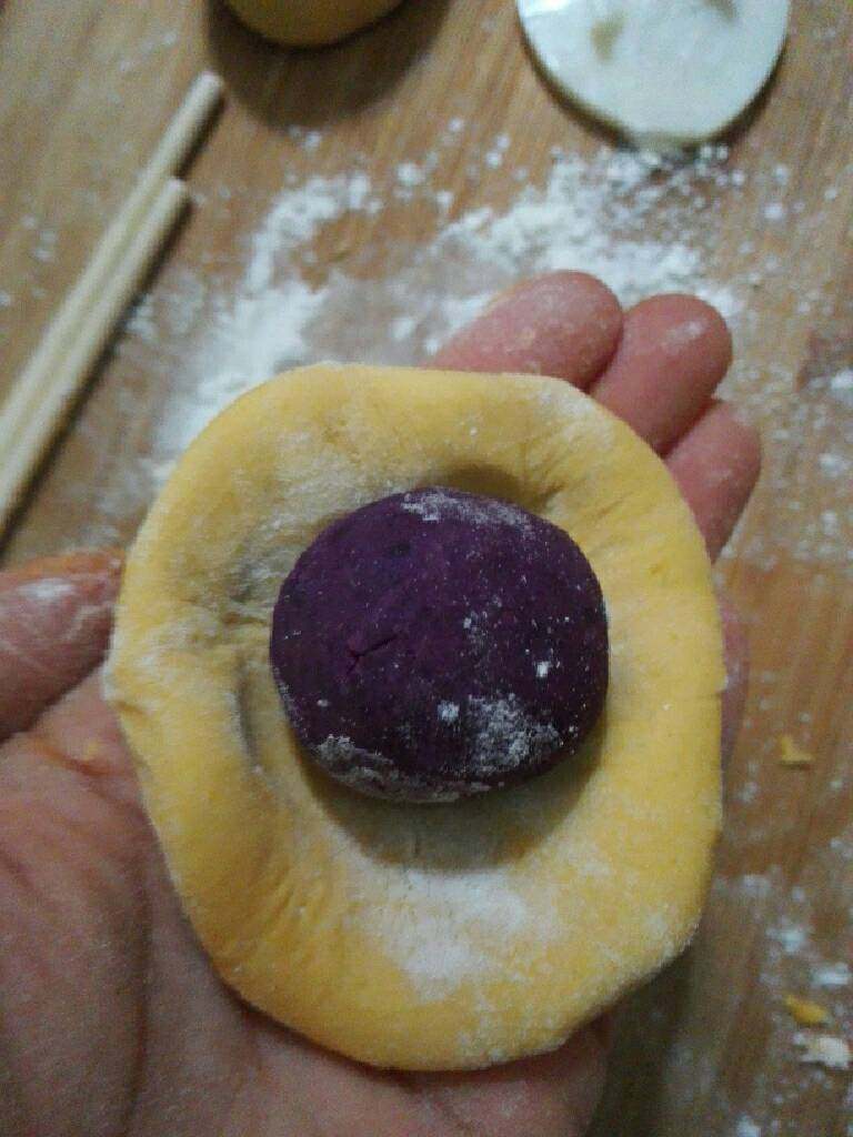 水晶南瓜饼,取约30g南瓜团，撮圆，放入紫薯球，包好，放入月饼磨具压出形状即可。（月饼磨具一定要摸一点油，防止沾，没磨具包好压扁就可以）。