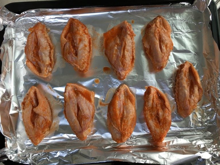 新奥尔良烤翅（烤箱版）,烤盘内垫入锡纸。把腌制好的鸡中翅，挨个放入烤盘内。