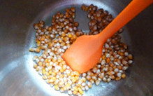 焦糖奶油爆米花,加盖后，中火加热，至开始听到有劈劈啪啪的声音时开始两手抓住锅手柄不断地晃动锅子，上下左右的，使玉米粒可以受热均匀。