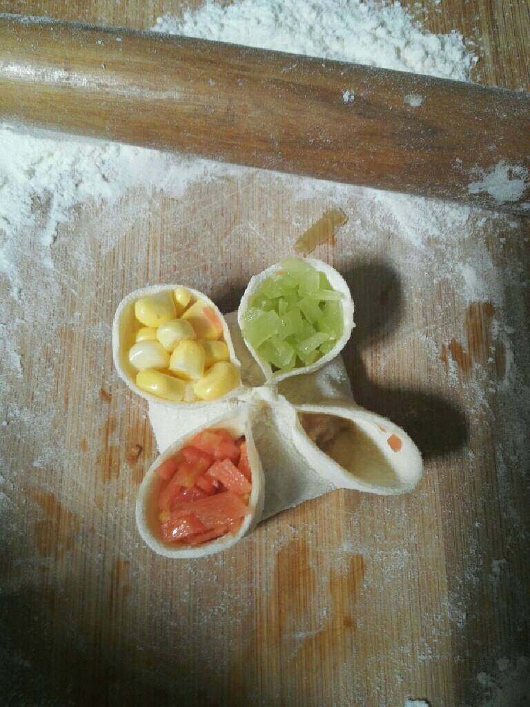 四喜蒸饺,将四个角整理一下，放入玉米粒，胡萝卜粒，木耳碎，窝笋粒。
