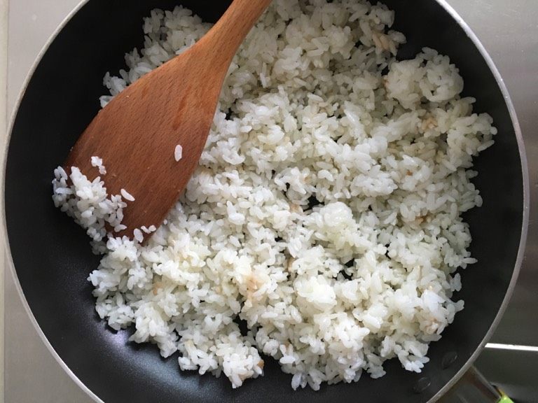 葱花蛋炒饭,油微热后倒入米饭，炒热、炒软。