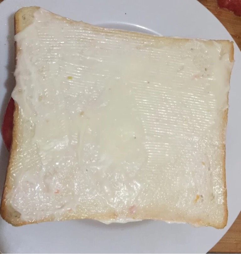 火腿蛋三明治,如图盖上第二片面包片，涂满沙拉酱