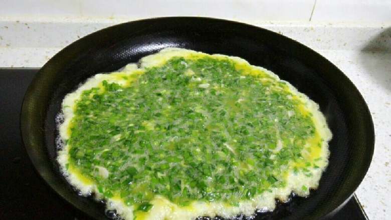韭菜鸡蛋饼,锅里倒入适量油，烧热后慢慢倒入韭菜蛋液，并移动锅使其成为一个圆形。