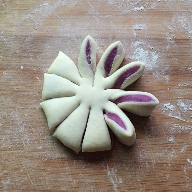 紫薯花朵馒头,把包好紫薯的面团压扁，切成10等份，每份面片都向一个方向扭转，使紫色面向上