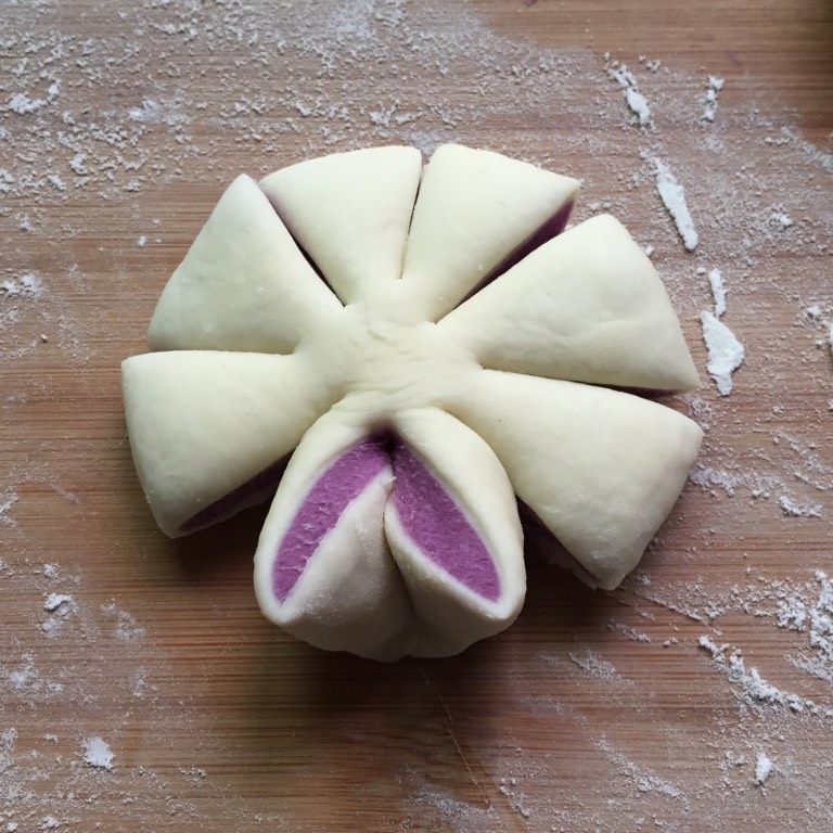紫薯花朵馒头,另一种花形，把面团压扁切成8等份，每两份一组，两面片同时向反方向扭转，紫色向上，捏紧下面两个角