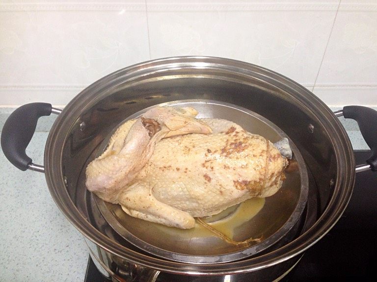 荷熏桂花鸡,取出腌好的鸡，入热水锅蒸30分钟；揭盖放入姜葱，继续蒸30分钟。蒸出的鸡汁留用。