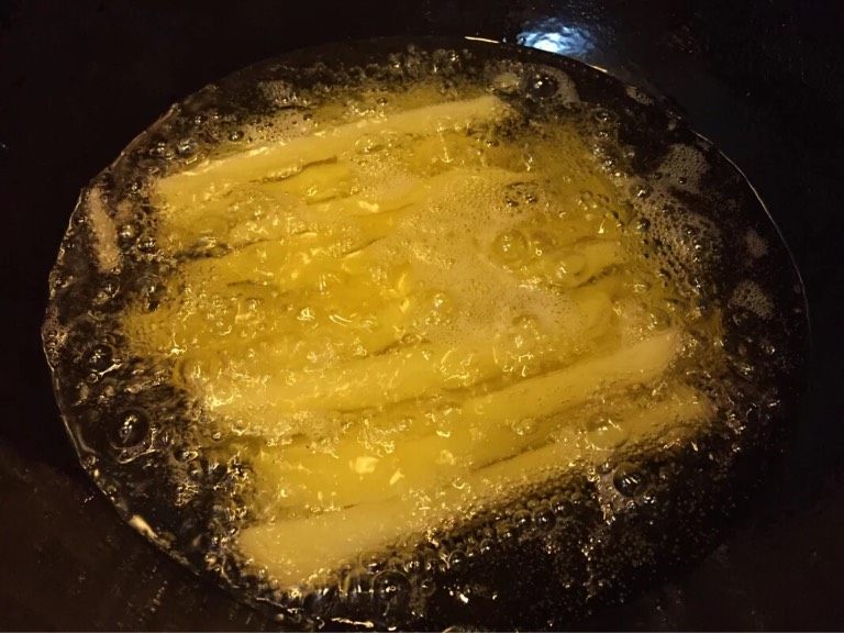 超简单炸薯条,如图油锅热油，油热放入沥干水分的土豆条