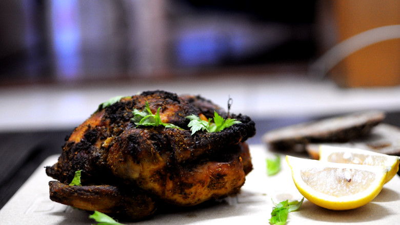 印度风味烤鸡,鸡稍冷却后撒上香菜叶，旁边放上蘸酱和柠檬。