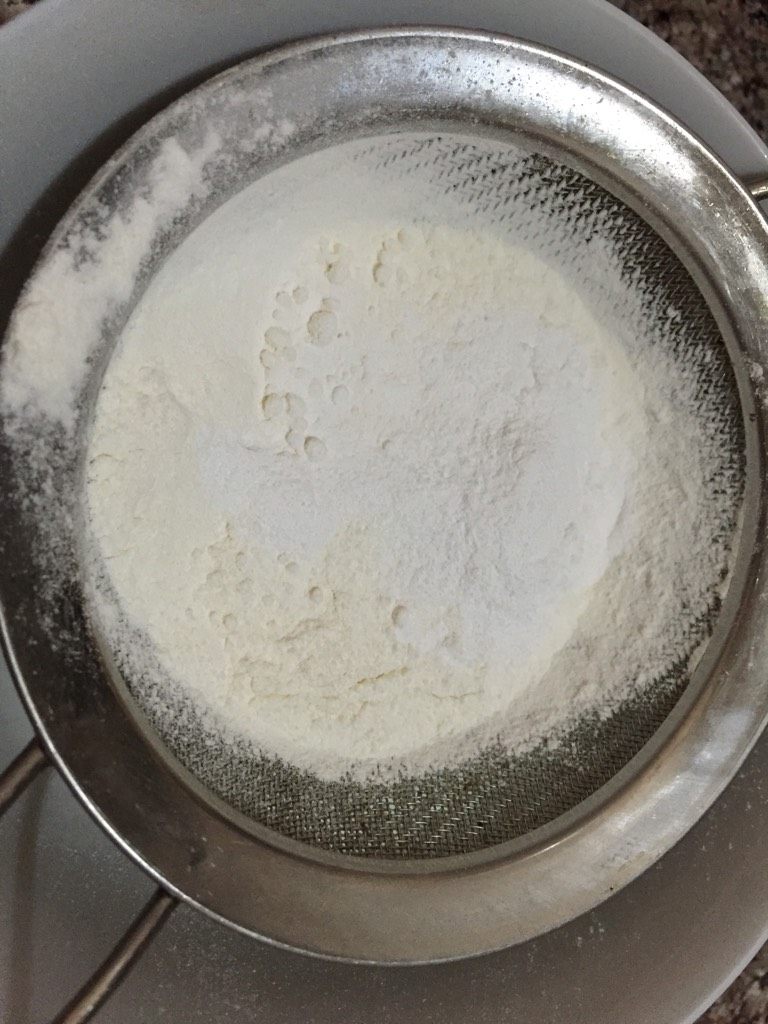 电饭煲蛋糕,如图牛奶中筛入低筋粉，加入食用油搅拌均匀。