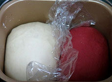 红曲双色吐司,将面包桶中的搅拌叶取掉，二个面团都放进面包机中，中间用保鲜膜分隔好，继续程序完成面团发酵至2-2.5倍