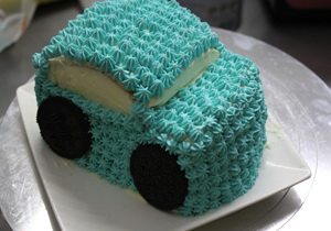 小汽车蛋糕,把剩下的淡奶油掺少许蓝色食用色素，用裱花袋在汽车表面挤上花，留出窗户