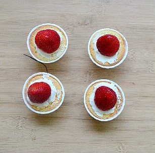 圣诞树杯子小蛋糕,小蛋糕切平面表，中间挤上一圈淡奶油或奶油霜，放上一个草莓。