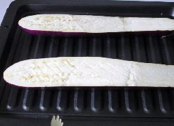 香辣肉糜烤茄子,把茄子洗净，从中间切开，在切面上划上几刀。放置烤盘上。