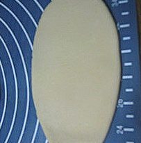 香酥板栗饼,然后口朝下放置，用擀面杖将面团擀开成椭圆形。卷起。