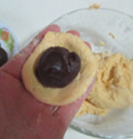 芝麻红薯豆沙饼,将适量的红薯面团按压成圆片， 中间放入豆沙馅， 搓成小球