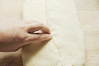 丹麦吐司,取出冷冻好的面团，擀成1cm左右厚的长方形，中间放入冻黄油片，面皮左右向内折包住黄油，收口处掐紧；