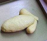 面包版圣诞火鸡,将面包生胚放入烤盘，小鸡腿形的面胚交叉放在大面胚的两边。进烤箱发酵至1.5倍大，烤箱低层放一碗鲜开水达到湿度的效果