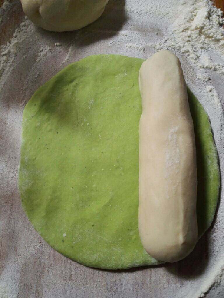 翡翠饺子,取适量菠菜面团擀成面皮，再放上撮成圆条白色面团。