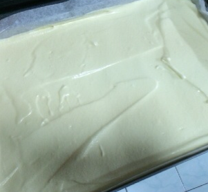 日式棉花蛋糕卷,将面糊从高处倒入盘中，用刮板抹平，表面喷水，入提前预热好的烤箱中层