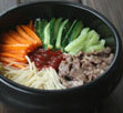 经典韩式石锅拌饭,将之前炒好的菜与青瓜丝分别摆放在米饭上，中间放入韩式拌饭辣酱