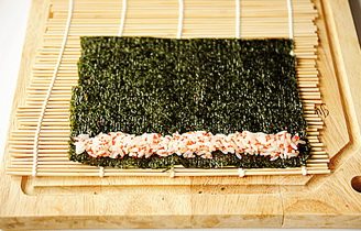 小花寿司,取一片海苔，一端铺上少量的鱼籽米饭；