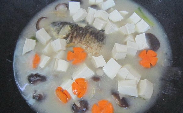 香菇豆腐鲫鱼汤,看到汤汁变白时加入水豆腐和胡萝卜花再煮2分钟左右