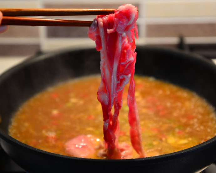 酸汤肥牛小米面,6. 肥牛卷洗净后放入沸腾的酸辣牛骨汤中。
