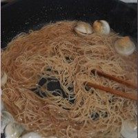 海鲜炒米粉,此时蛤蜊还没张口，倒入米粉，改用筷子不断挑起米粉抖落着翻炒。