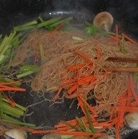 海鲜炒米粉,炒到锅中汤汁基本收尽，倒入蔬菜丝继续翻炒至米粉干爽，蛤蜊开口。
