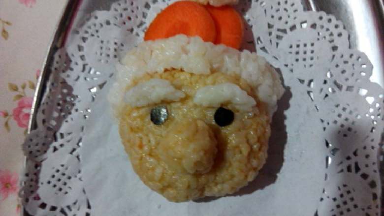 圣诞老人,番茄汤米饭滚成圆球，制作成圣诞老人的大鼻子，海苔剪成圆形，放在眉毛下面。